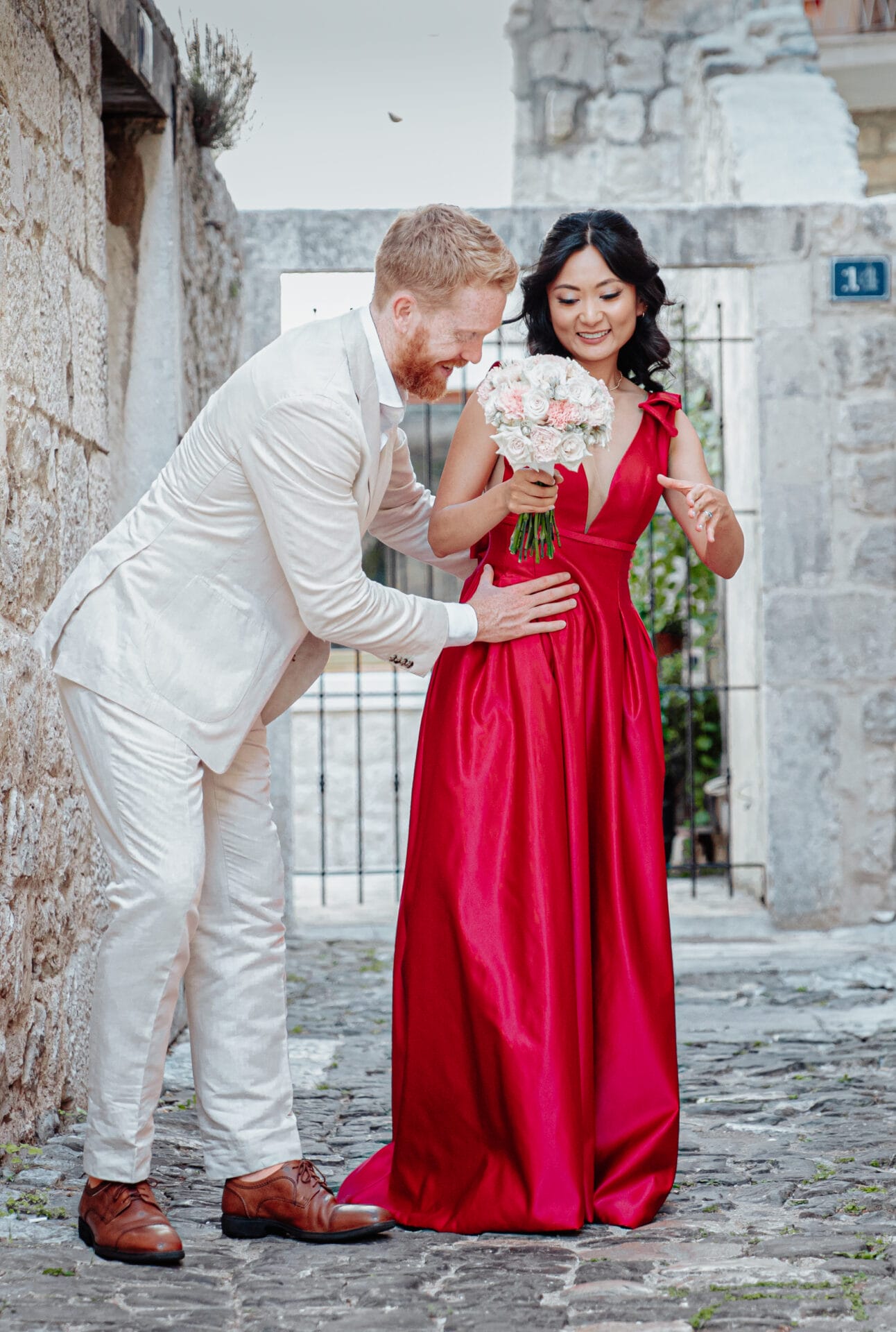 newlyweds smiling holding roses by ruby photography
